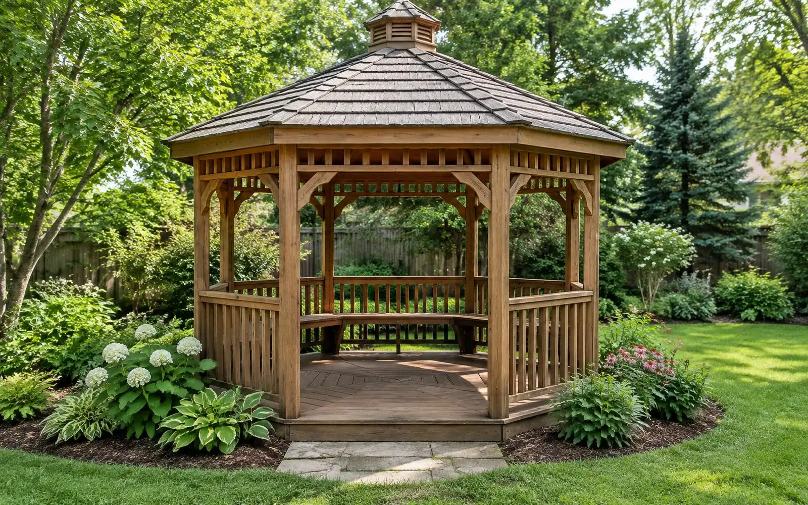 Octagonal wood gazebo with a shingled roof and railings in a green backyard garden